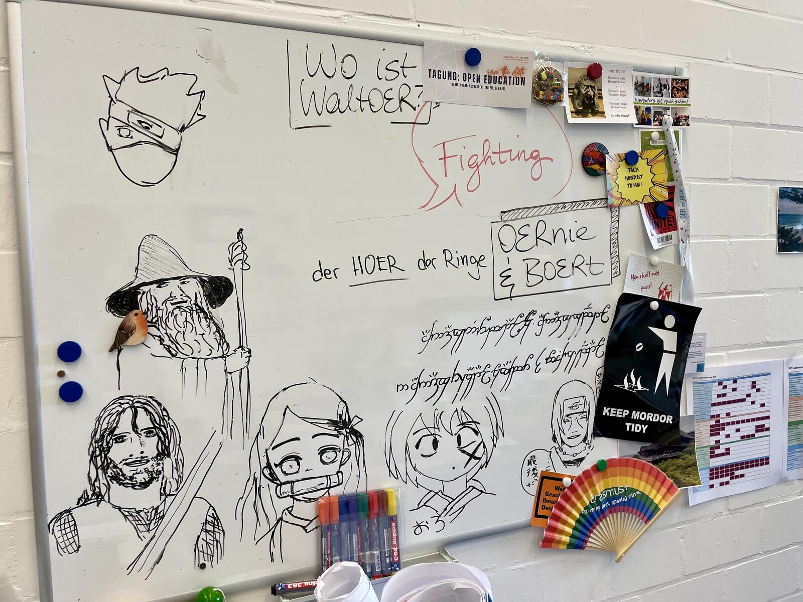 Whiteboard im Büro vom digiLL-Team mit Comic-Zeichnungen und lustigen Wortspielen zu OER wie "Wo ist WalthOER?", "OERnie & BOERt" oder "der HOER der Ringe"