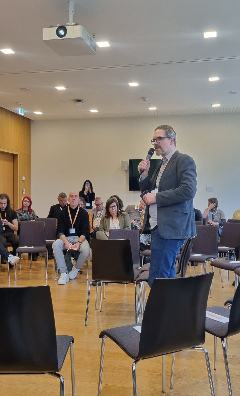 Johannes vom DIPF mit Mikrofon in der Hand als Moderator beim Trialog von usOER, researchOER und providOER beim OERinfo-Fachtag 2025.