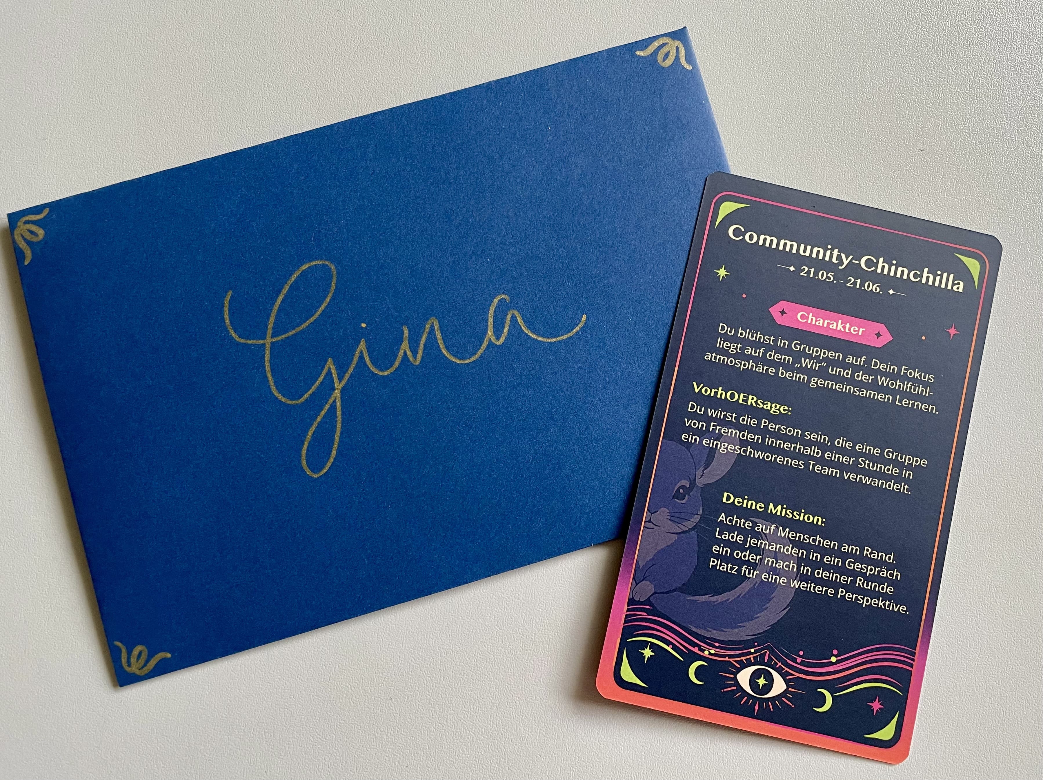 Blauer Umschlag mit dem handgeschriebenen Namen „Gina“ neben einer hOERoskop-Karte „Community-Chinchilla“ mit Charakter, VorhOERsage und Mission.